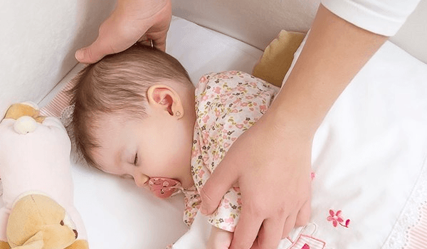 Baby mit Kuscheltier im Babybett